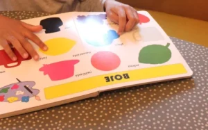 Ein Kind verfolgt mit dem Finger die Farbnamen in einem Kinderbilderbuch.