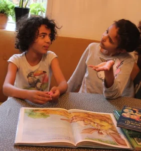 Ein freundliches Gespräch zwischen Mädchen beim Vorlesen eines Bilderbuchs.